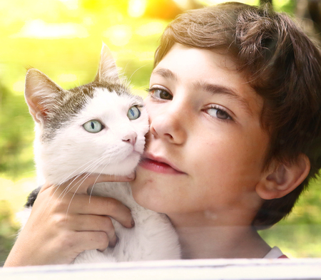 preteen handsome boy with tom cat close up photo on the summer garden backgroundの写真素材