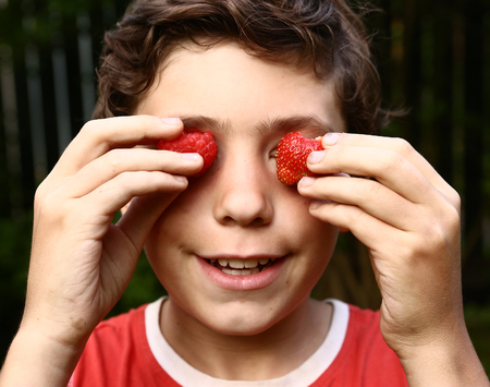 preteen boy cose up portrait with strawberry eyesの写真素材