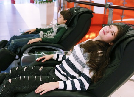 teen kids boy and girl in shopping mall lay in massage chair close up photoの写真素材