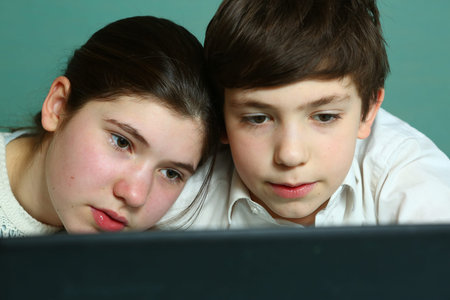 siblings brother and sister watch footage on laptop close up portrait