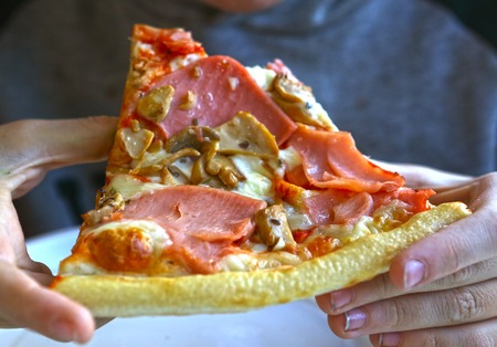 pizza with ham and mushrooms close up photo in handsの写真素材