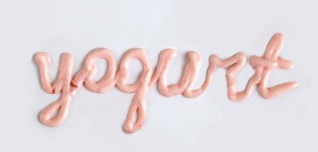 pink fruit yogurt inscription on white background close up photoの写真素材