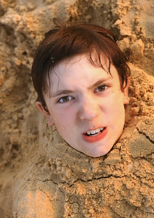 preteen handsome boy head on the sand background close up photoの写真素材