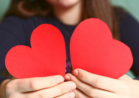 girl hold red paper two valentines hearts close up photoの写真素材