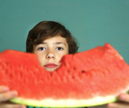preteen handsome boy biting water melon close up portrait
