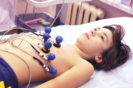 preteen boy under ecg test with doctor close up photo