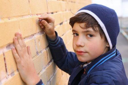 preteen handsome boy in blue hat drawing on the wall close up portrait