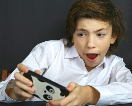 preteen handsome boy play computer game on his cell phone. Boy addicted to phone games. Gaming boy