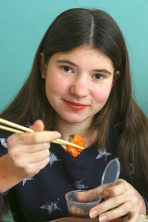 pretty teen girl with sushi roll close up portrait, teenager girl eating japanese sushiの写真素材