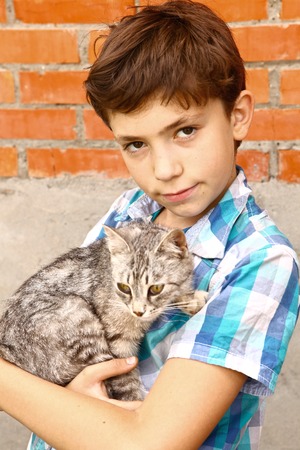preteen handsome boy with siberian tom cat close up country summer portrait with cottage house on the backgroundの写真素材