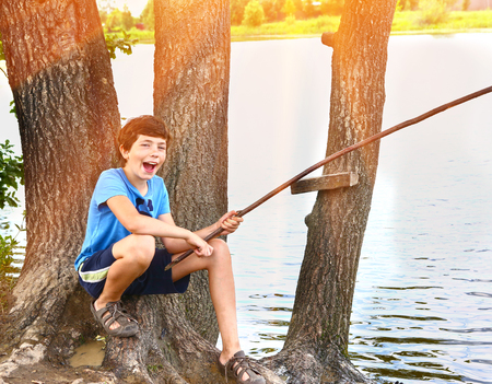 preteen happy boy fishing on the lake close up summer portraitの写真素材