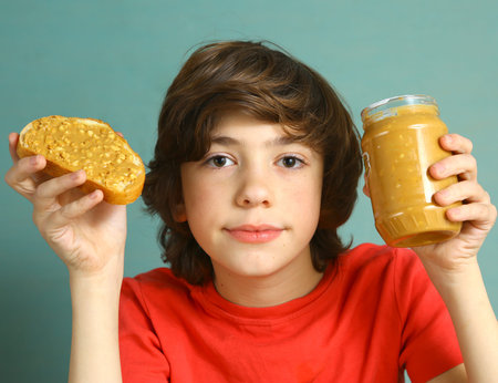 preteen boy hold peanut butter with nut pieces sandwich with jar close up portrait