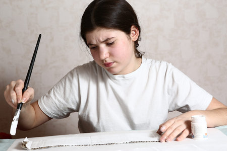 Girl smiling and painting white paint paper brushの写真素材