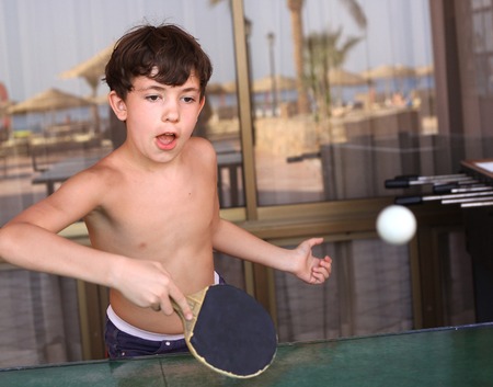teenage kid boy play tennis table ping pong close up photo on the outdoor beach backgroundの写真素材