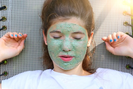 teenager girl in blue glue mask outdoor summer portrait on chaise loungeの写真素材