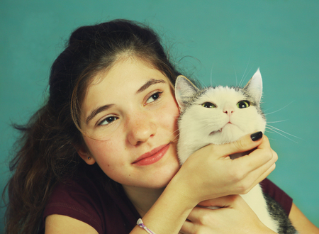 teen girl with long brown hair and cat hugging close up portraitの写真素材