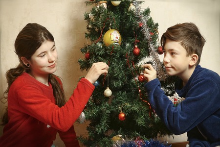 teen siblings girl and boy decorating christmas tree close up photoの写真素材
