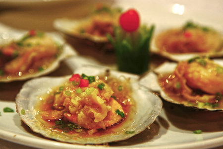 clams cooked on plate in restaurant with vegetables and sauce