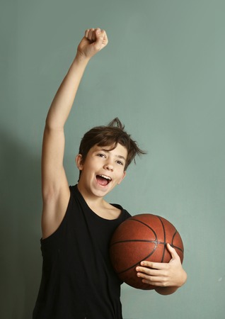 teeb boy with basketball ball and sleeveless t-shirt hand up in victory gestureの写真素材