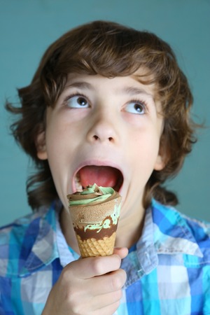 preteen boy with icecream cone make fun grimacing close up photoの写真素材