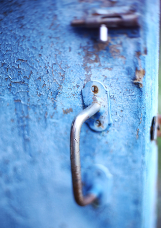 old vintage latch lock on blue shabby cracked painted door close up photoの写真素材