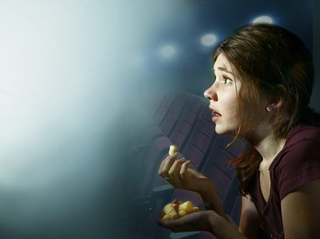 teenager girl watching horror movie with pop corn in cinemaの写真素材