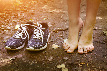 bare feet stay tiptoe and trainer shoes close up photo on the forest pathの写真素材
