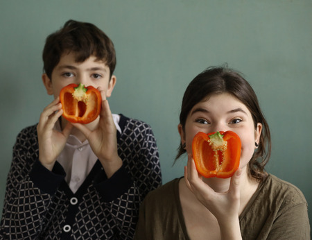 teenager siblings brother and sister with red sweet cut bulgarian paprika pepper funny photoの写真素材