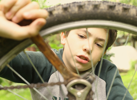 teen boy repair bicycle tire close up summer photoの写真素材