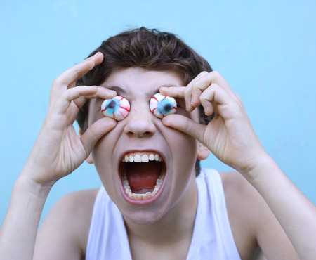 teenager boy with jujube marshmellow eyes smiling open mouth close up portraitの写真素材