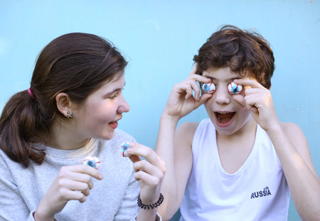 teenager boy and girl with jujube marshmellow eyes smiling open mouth close up portraitの写真素材