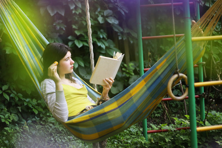 teenager girl lay in hammock with book and kitten outdoor summer garden photoの写真素材