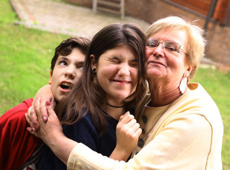 grandma hug grand children they grimacing close up summer outdoor photoの写真素材