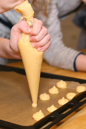 profiteroli cooking process with dough balls, hands with special culinary tube cone to extrude doughの写真素材