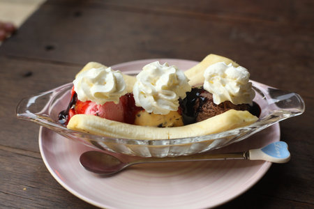 banana split ice cream dessert in saucer with chokolate icing and cream close up photo