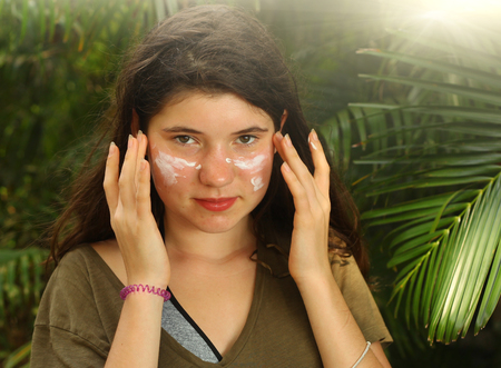 teenager girl using sun protecion cream on face close up photoの写真素材