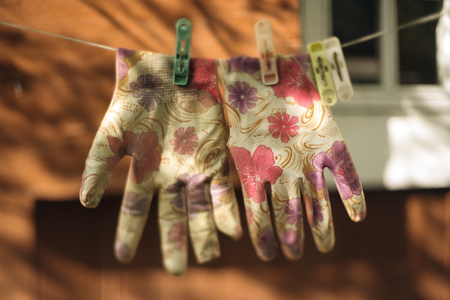 rustic vintage photo of floral print garden gloves drying on rope on cottage house backgroundの写真素材