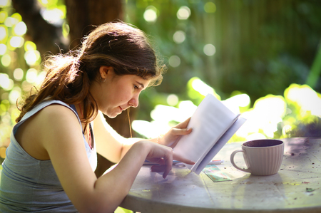 teenager student girl reading book with tea cupの写真素材