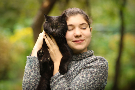 summer sunny photo of teenager girl hug blackcat close up outdoor photoの写真素材