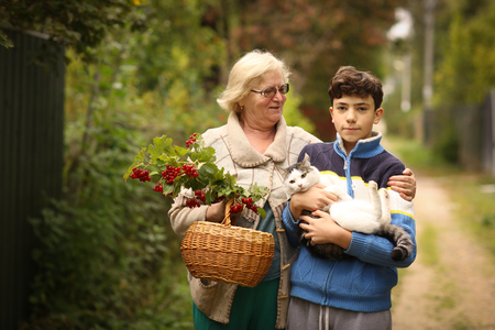 grandmother with grandson with viburnum and cat close up photo on green garden backgroundの写真素材