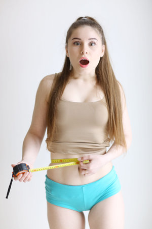 close up photo of model girl measure her waist with measuring tape in blue pants close up photo...