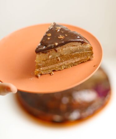 peace of cut pear caramel cake with cream mousse and chocolate glaze with nuts close up photoの写真素材