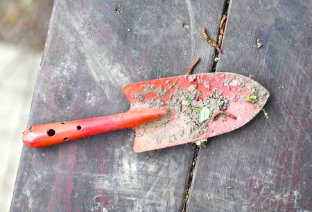 garden red spade shovel closeup photo with soil on the wooden benchの写真素材