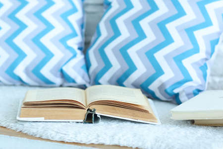 opened book with blue pattern pillows in the bedroom closeup photoの写真素材