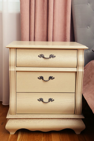 fragment of pink bedroom with white wooden sideboard closeup photo
