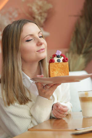 blond girl cube formed dessert with cream, raspberry, blueberry and marshmallow topping closeup photoの写真素材