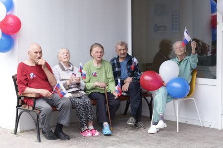 Russia, Moscow, June 11, 2022: Old people in elderly house with colored balloons celebrate Day of Russia closeup outdoor photo.のeditorial素材
