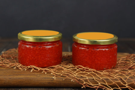natural red caviar in glass jar closeup photo on kitchen board