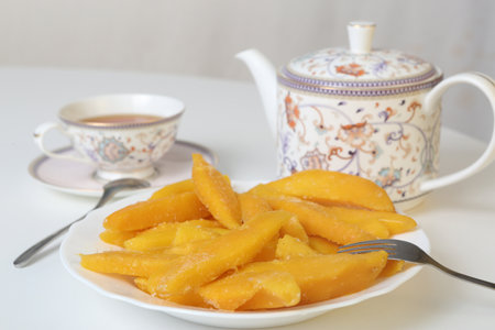 healthy eating slices of yellow mango closeup photo with tea cup and cattleの写真素材