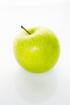 A whole granny smith green apple against a plain whit backgroundの写真素材